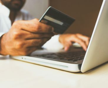 person using laptop computer holding card